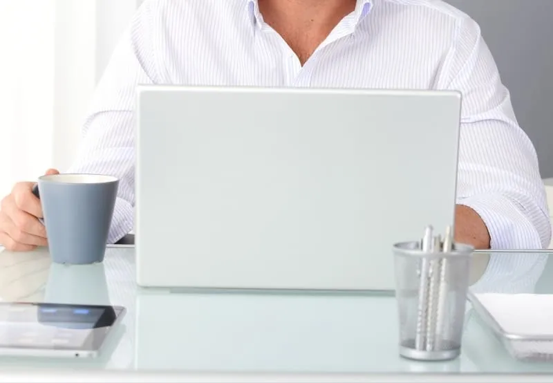 Dental practice manager planning marketing strategy at modern office desk with laptop and coffee